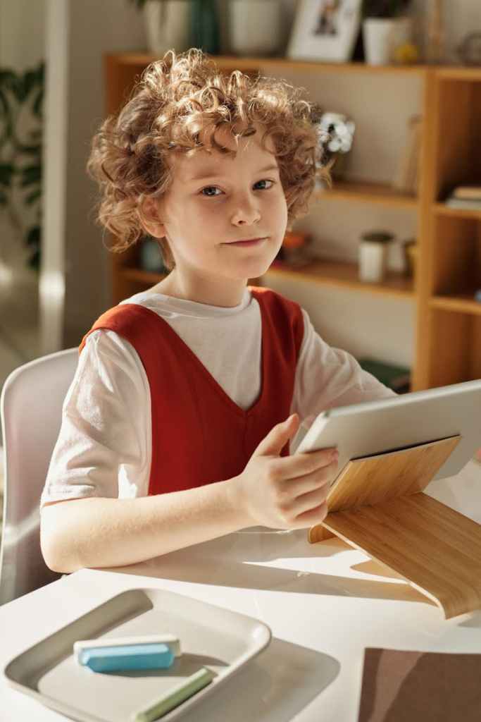 pexels-photo-4145075-4145075 Curly-haired girl using tablet for online learning at home, sitting at desk.